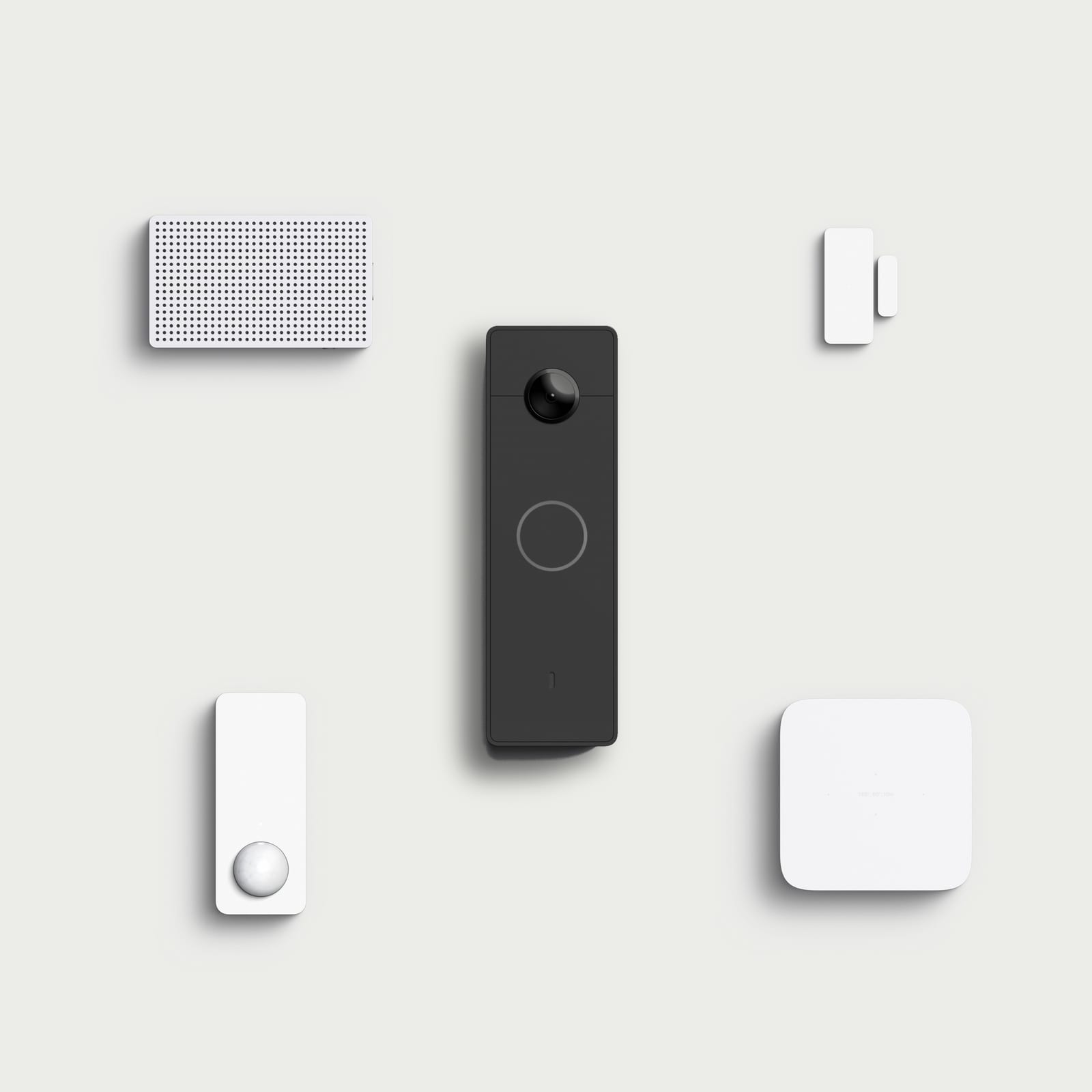 Five Simple Things devices arranged on a pale ground: the chime, the entry sensor, the motion sensor, and the radar sensor around the doorbell camera in the centre