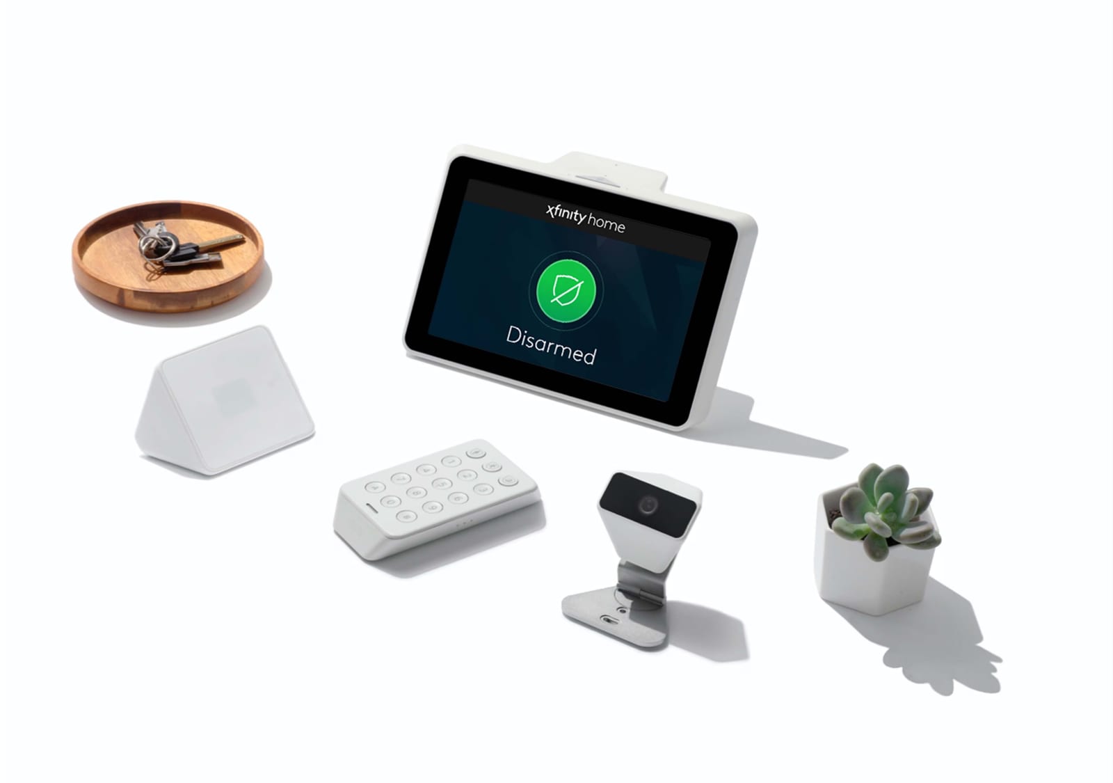The Xfinity Home kit laid out flat: touchscreen showing the system disarmed, keypad, sensors, and camera
